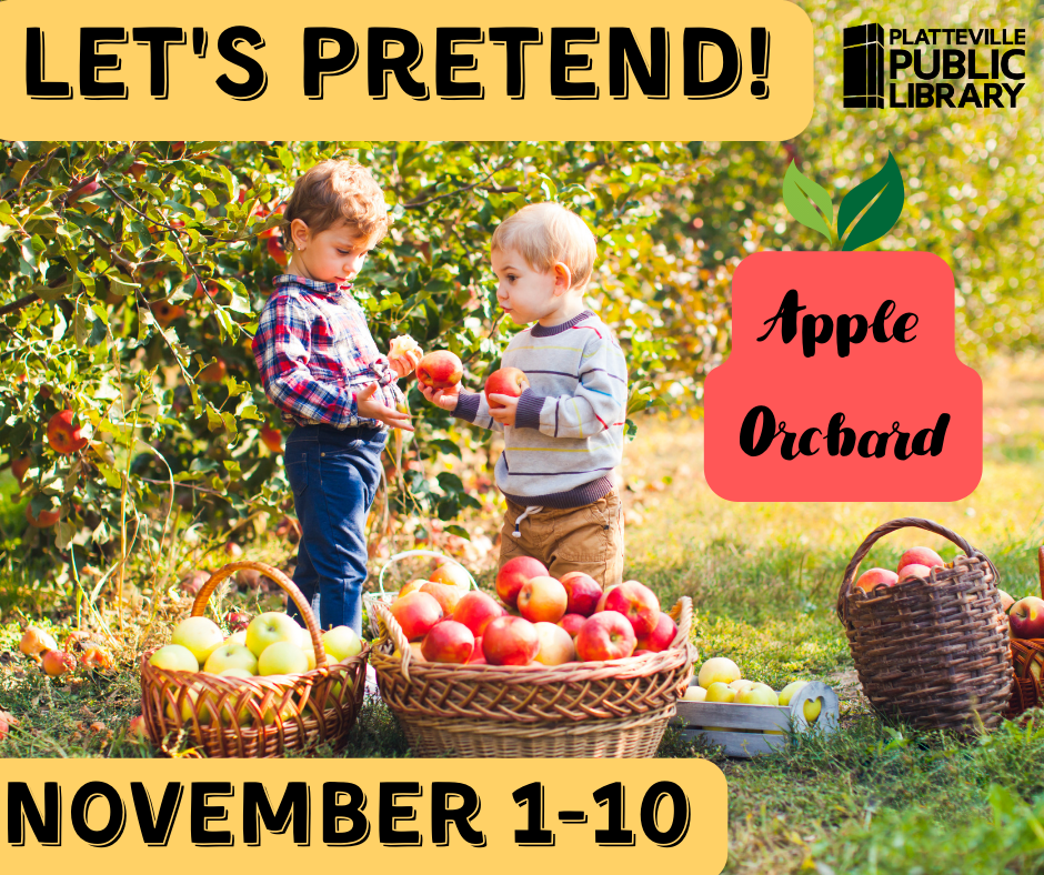 Two toddlers looking at apples from a basket in an orchard.